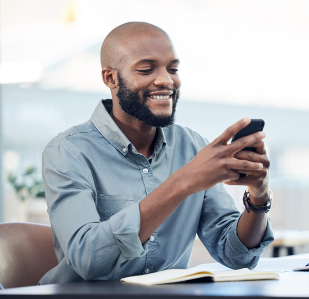 Image of a black man smiling while using a smartphone with VoIP.ms Emergency Calling Service